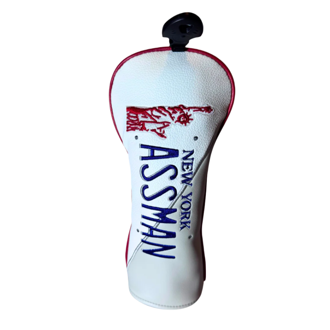 A red and white Assman golf head cover with 'ASSMAN' written in bold blue letters and a graphic of the Statue of Liberty in red.